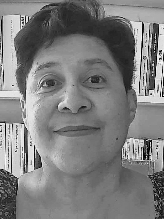 Portrait en noir et blanc d'Isabelle Augier-Jeannin, souriante, devant une bibliothèque